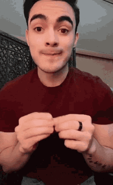 a man wearing a red shirt has a tattoo on his wrist that says ' i love you '