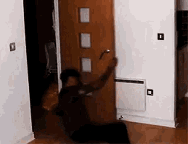 a man is kneeling down in front of a door in a hallway .