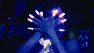 a woman with glow in the dark nails is singing in a dark room