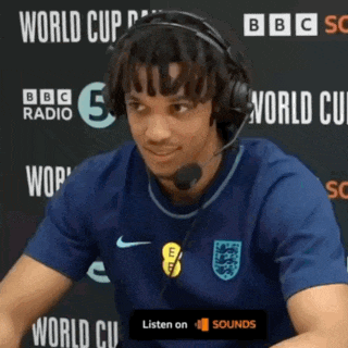 a man wearing headphones is sitting in front of a wall that says world cup