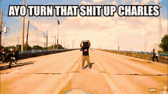 a man carrying a box on his head stands on a highway with the words " ayo turn that shit up charles "