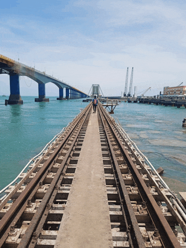 a bridge over a body of water with a man walking on the tracks