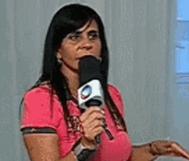 a woman is holding a microphone in her hand and talking into it .