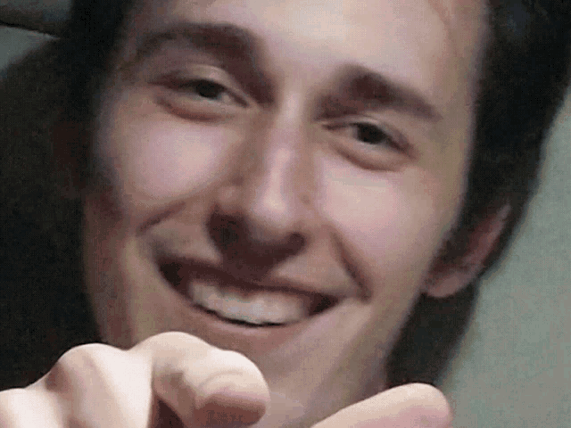 a man is smiling while pointing at the camera