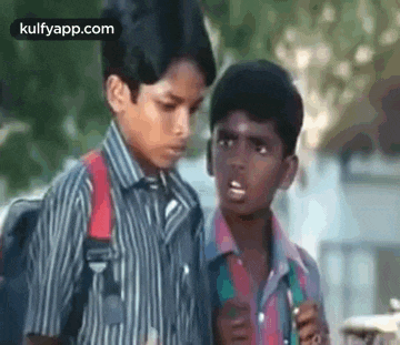 two young boys are standing next to each other on a sidewalk .