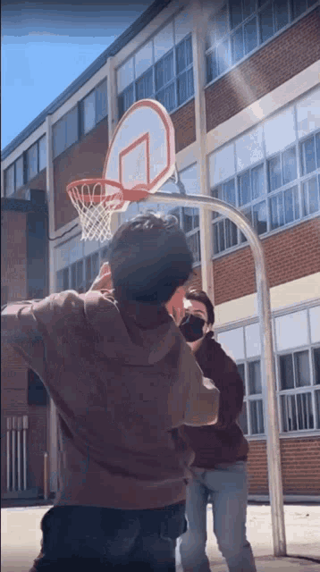 a man wearing a mask shoots a basketball through a hoop