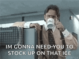 a man in a suit and tie is drinking from a cup while leaning on a refrigerator .