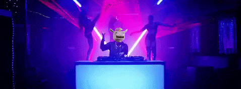 a man in a cowboy hat is sitting at a dj 's table in a club .