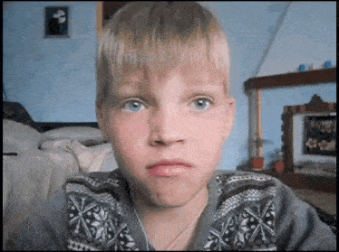 a young boy with blue eyes is making a funny face .