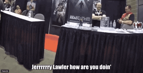 a man sitting at a table with a sign that says ' jerry lawler how are you doin ' on it