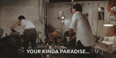 two men are standing in a messy room and one of them is saying `` your kinda paradise '' .