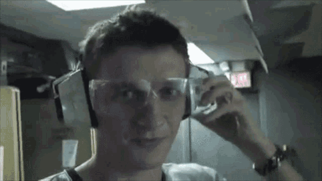 a man wearing ear muffs and safety glasses is looking at the camera