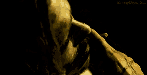 a close up of a person 's face in a dark room with a hand reaching out .