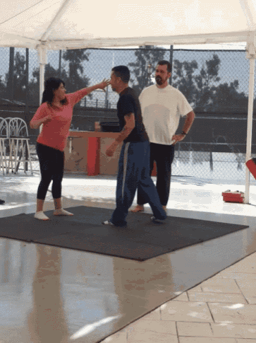 a man and a woman are standing on a mat under a tent