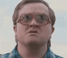 a man wearing glasses and a plaid shirt is making a face .