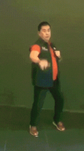 a blurred image of a man in a green vest and orange tie