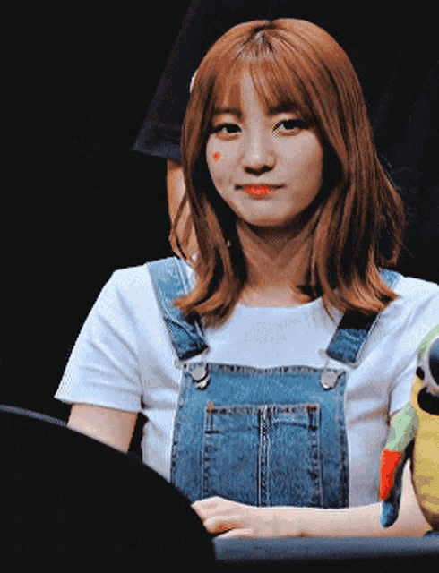 a young woman wearing overalls and a white shirt