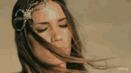 a close up of a woman 's face with her hair blowing in the wind .