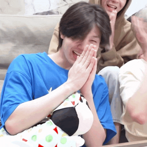 a man in a blue shirt is holding a stuffed animal and laughing