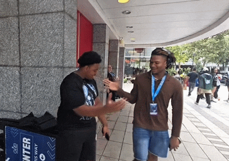 a man talking to another man in front of a blue box that says " enter "