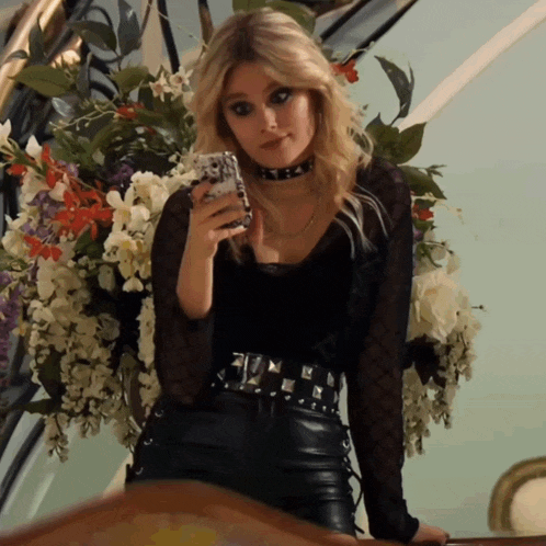 a woman is taking a picture of herself in front of a vase of flowers