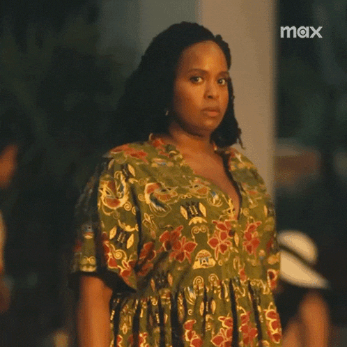 a woman in a green dress is looking at the camera .