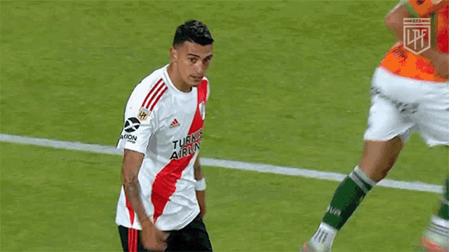 a soccer player in a red and white adidas jersey is standing on a field .