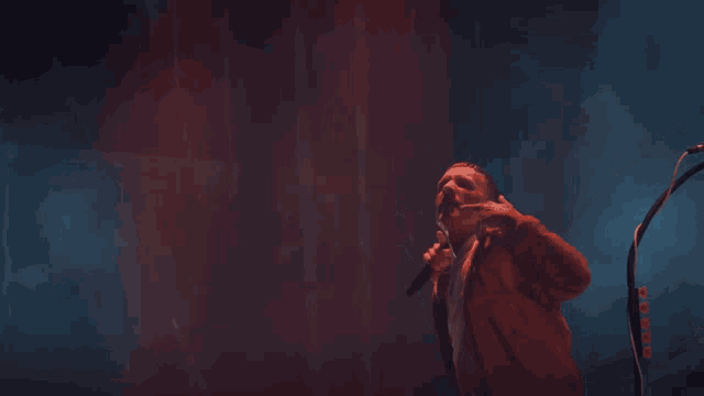 a man singing into a microphone with his finger pointing
