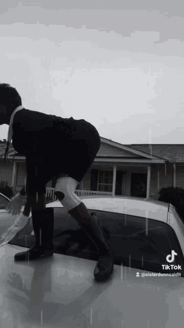 a person standing on the roof of a car with a tiktok sticker on it