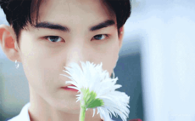 a young man is holding a white flower in his hand