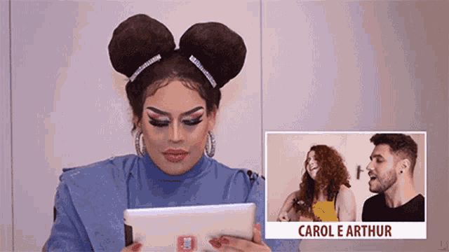 a drag queen is holding a tablet in front of a picture of carol e arthur ..