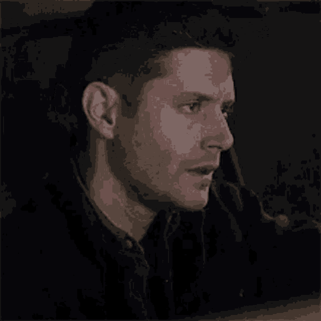 a close up of a man 's face in a dark room looking at something .