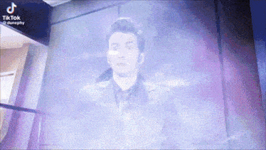 a man in a suit and tie is standing in front of a wall with a purple background .