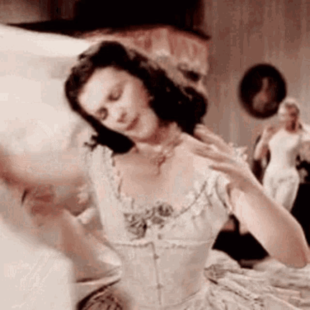 a woman in a white dress is dancing in a room with other women .