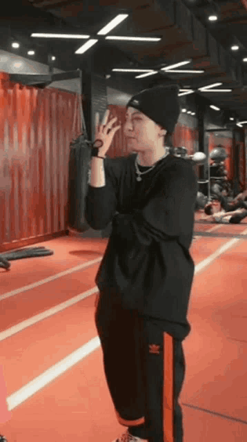 a man in a black shirt and black pants is standing on a red track in a gym .
