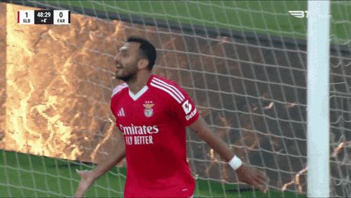 a soccer player wearing a red emirates fly better jersey celebrates