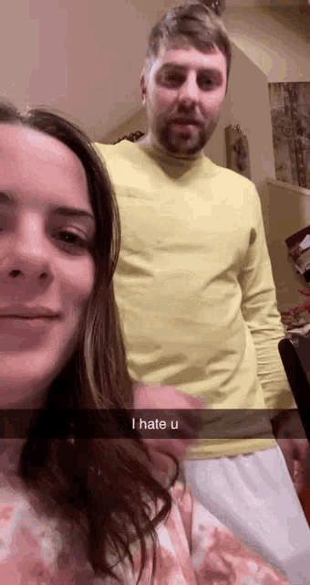 a man in a yellow shirt is standing next to a woman in a pink blanket .