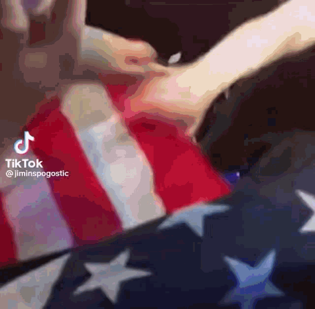 a person is laying on a bed with an american flag behind them .