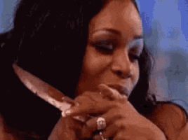 a woman is holding a knife in her hand and making a funny face .