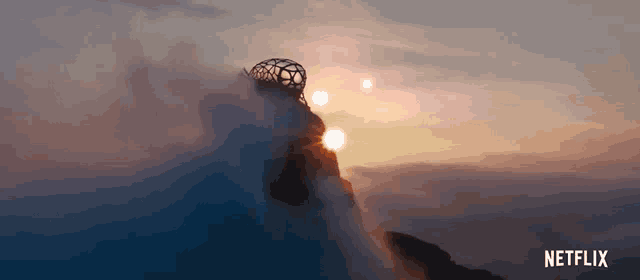a netflix ad shows a sunset over a mountain with the sun shining through the clouds
