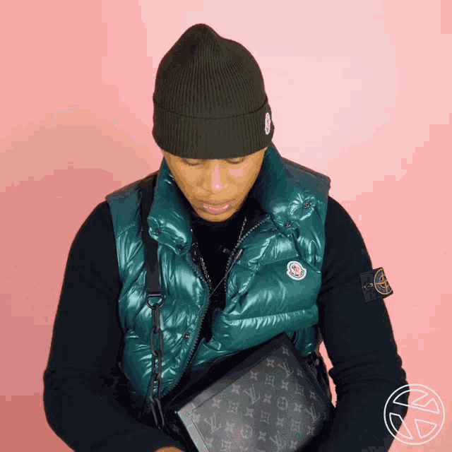 a man wearing a black sweater and a green vest with a moncler logo on it