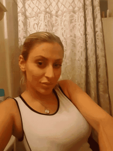 a woman taking a selfie in a bathroom with a shower curtain behind her