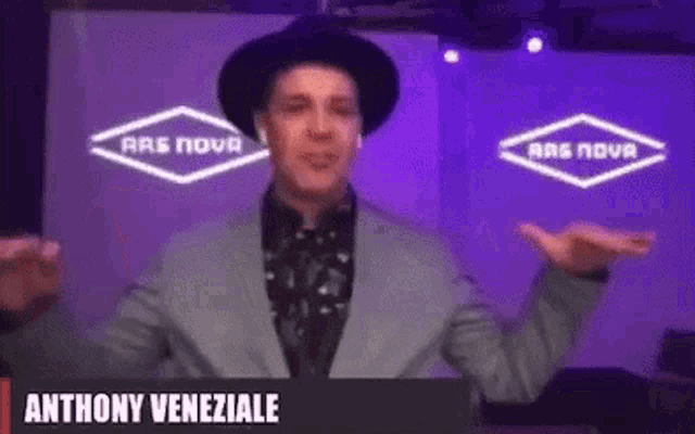 a man in a suit and hat is standing in front of a sign that says anthony veneziaele