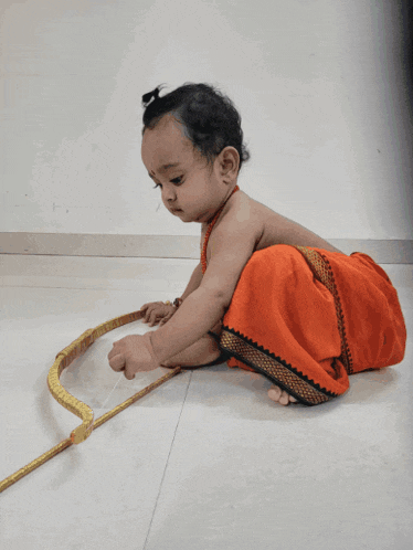a baby is crawling on the floor playing with a rope