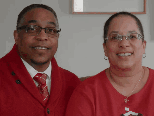 a man and woman are posing for a picture and the man is wearing a red sweater and tie