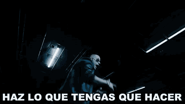 a man in a dark room with the words haz lo que tengas que hacer