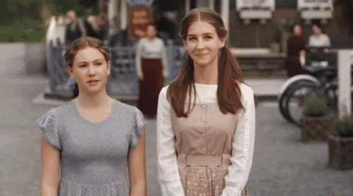 two young women are standing next to each other in front of a building that says ' a ' on it