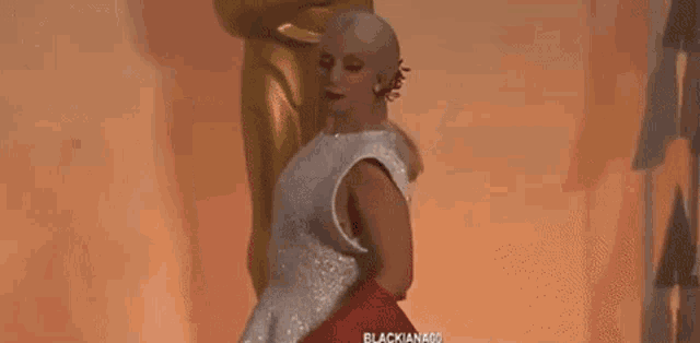 a woman in a white dress is standing next to an oscar statue and a tweet from chart data