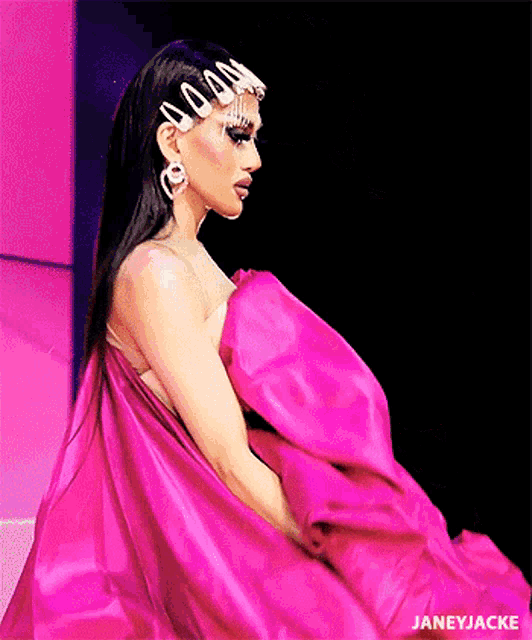 a woman in a pink dress is walking down the runway at a fashion show .