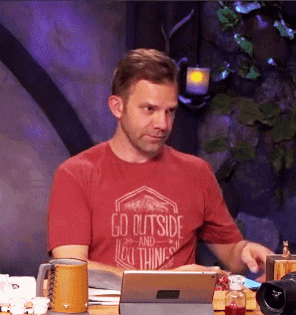 a man wearing a red shirt that says go outside and do thing
